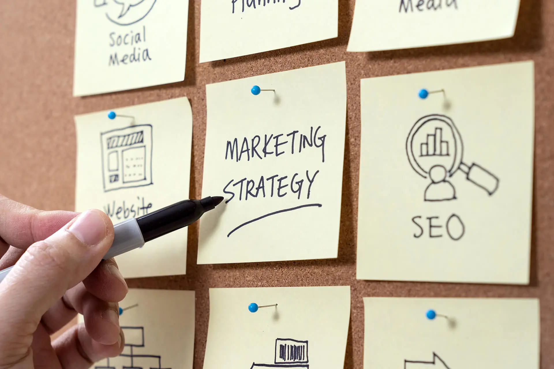 Hand writing marketing strategy on sticky note