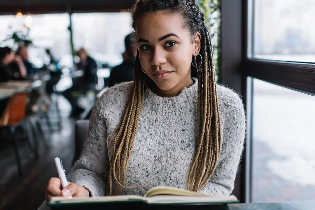 Woman writing in notebook at café