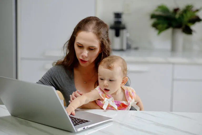 Moeder en baby met laptop in keuken