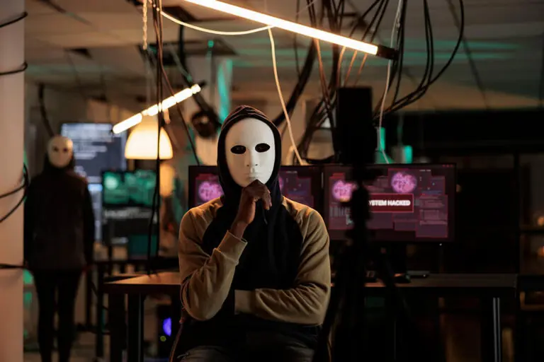 Hacker in masker met computers op achtergrond